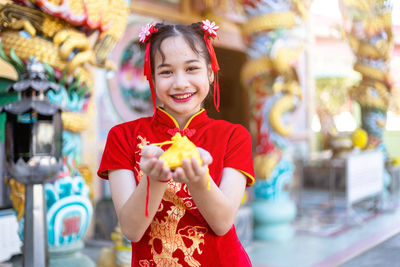 Portrait of smiling girl holding decoration against temple