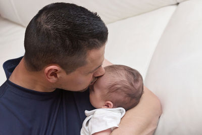 Rear view of father with baby on bed