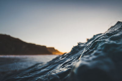 Close-up of rocks at beach against sky during sunset