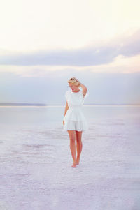 Full length of woman standing at beach against sky