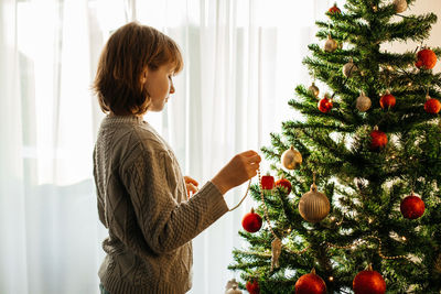 The girl decorates the christmas tree for the holiday. preparing for christmas and new year. 