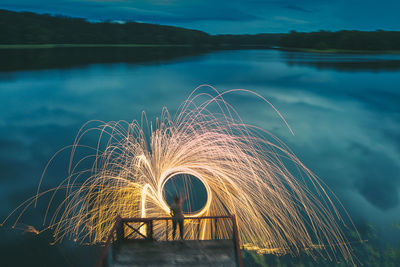 Person making wire wool at lake during dusk
