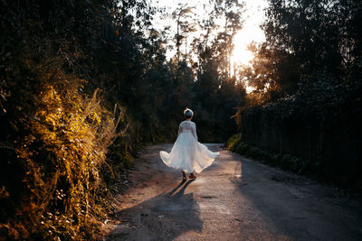 Rear view of woman walking on footpath amidst trees