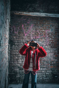 Full length of man standing against brick wall