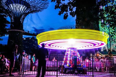 People at amusement park ride at night