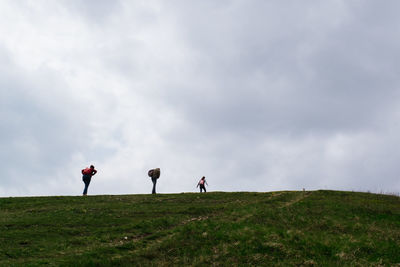 People standing on field against cloudy sky
