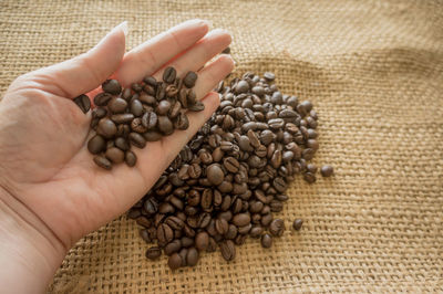 Cropped hand holding roasted coffee beans