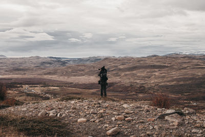 Rear view of man standing on mountain against sky