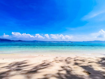 Scenic view of beach against blue sky