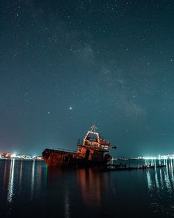 The old rusty ship in shallow water against night sky with milky way