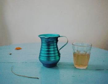 Close-up of glass of jar on table against wall