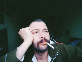 Man looking away while smoking cigarette