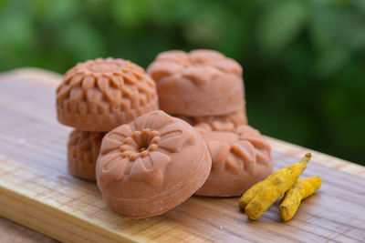 Round orange soap in the form of flowers with turmeric on a green background