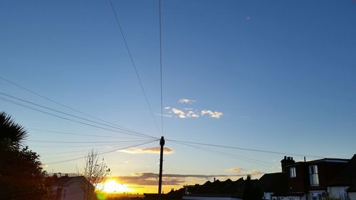 Low angle view of electricity pylon at sunset