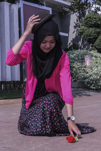 Young woman picking rose on footpath