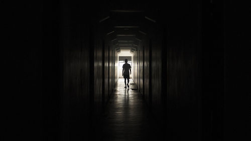 Rear view of man walking in corridor of building