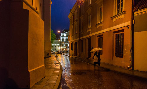 People walking on wet street at night