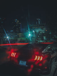 Cars on illuminated city street at night