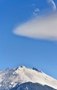 Peak mountain covered with snow under blue sky and a white cloud