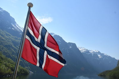 Red flag on snowcapped mountains against sky