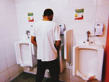 Rear view of man standing in bathroom