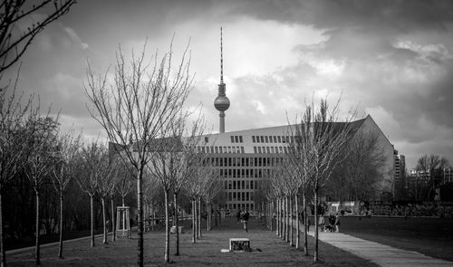 View of communications tower in city against cloudy sky