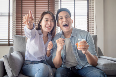 Happy friends sitting on sofa