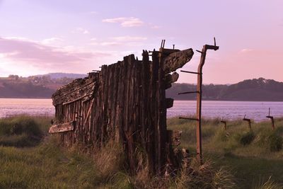 Wooden posts on mountain against sky at sunset