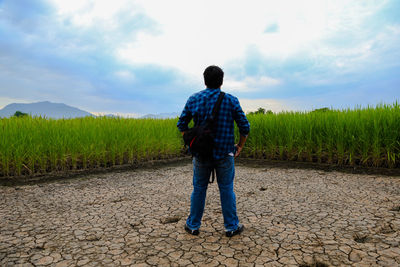 Rear view of man standing on field against sky