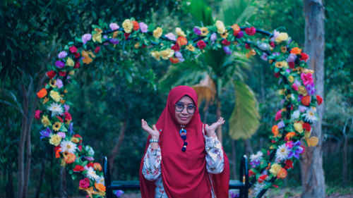 Portrait of young woman standing by flowering plants