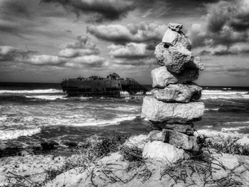 Rocks on shore at beach against sky
