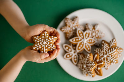 Ginger christmas cookies in children's hands on the background of the christmas tree.