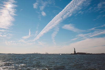 Statue of liberty by hudson river against sky