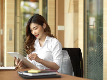 Young woman using phone while sitting on table