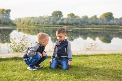 Boy sitting on grass by lake