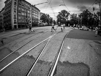 People walking on railroad track in city