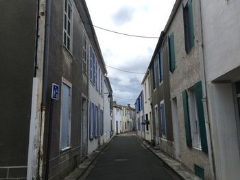 Empty road amidst buildings against sky