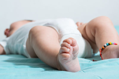 Low section of baby on bed at home