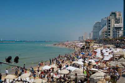 People on beach against clear sky in city