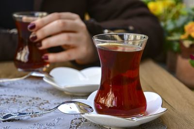 Midsection of woman drinking glass on table