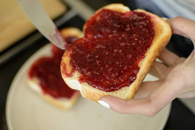 Cropped hand applying jam on bread