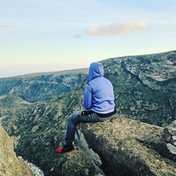 Rear view of man on rock by mountains