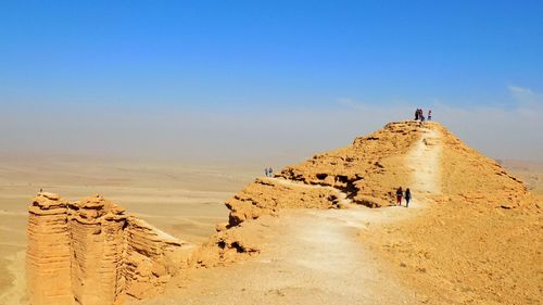 People on desert against clear sky