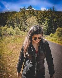 Young woman wearing sunglasses standing against plants