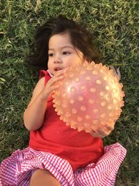 High angle view of girl with ball lying on grassy field