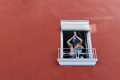 Woman on window against wall