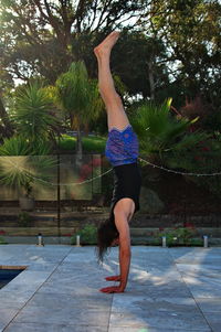 Young man doing handstand near the pool