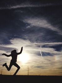 Silhouette of person dancing against sunset sky