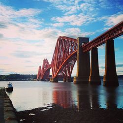 Low angle view of forth rail bridge over river against cloudy sky