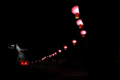 Low angle view of illuminated lanterns hanging against sky at night